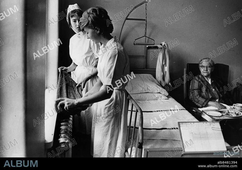 Göteborg 1964-12-06 - Sahlgrenska Sjukhuset - Vårdbiträdet Rose-Marie Petersson och avdelningssköterskan syster Ingegerd Nordlund försöker lindra värmen i ett av sjukrummen genom att lägga våta dukar på de kokheta elementen. I Bakgrunden patienten fru Hilda Olofsson. *** Local Caption *** GT. KAMERAREPORTAGE.