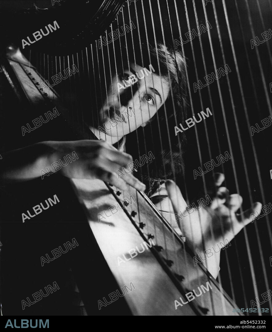 Student Of The Harp -- Close-Up Of A Harpist : Sheila Bromberg seen through the strings. January 31, 1951. (Photo by Tom L. Blau, Camera Press).