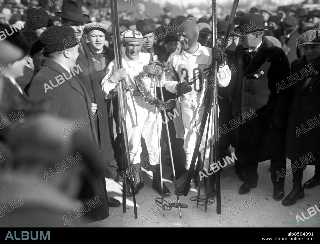 Göteborg 11 mars 1928 Vasaloppet. 1928 åkte Per-Erik Hedlund nu för Särna och Sven Utterström, Boden, dött lopp och åkte i mål hand i hand på tiden 5.33.23. Båda "trädde armarna i lagerkransen och läto film- och kameramän föreviga det stolta ögonblicket". Kranskulla: . Stina Eriksson . Foto: Kamerareportage *** Local Caption *** . KAMERAREPORTAGE.