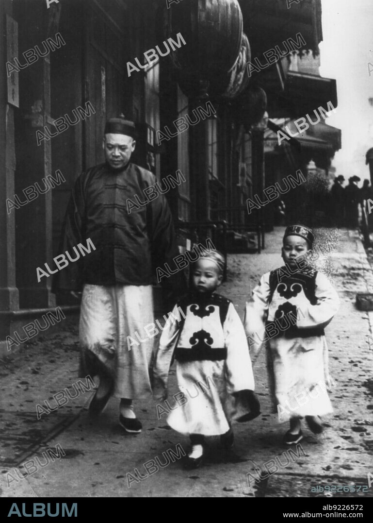 ARNOLD GENTHE. A family from the Consulate, San Francisco Chinatown, 1904. Chinese man and two Chinese children walking on pavement.