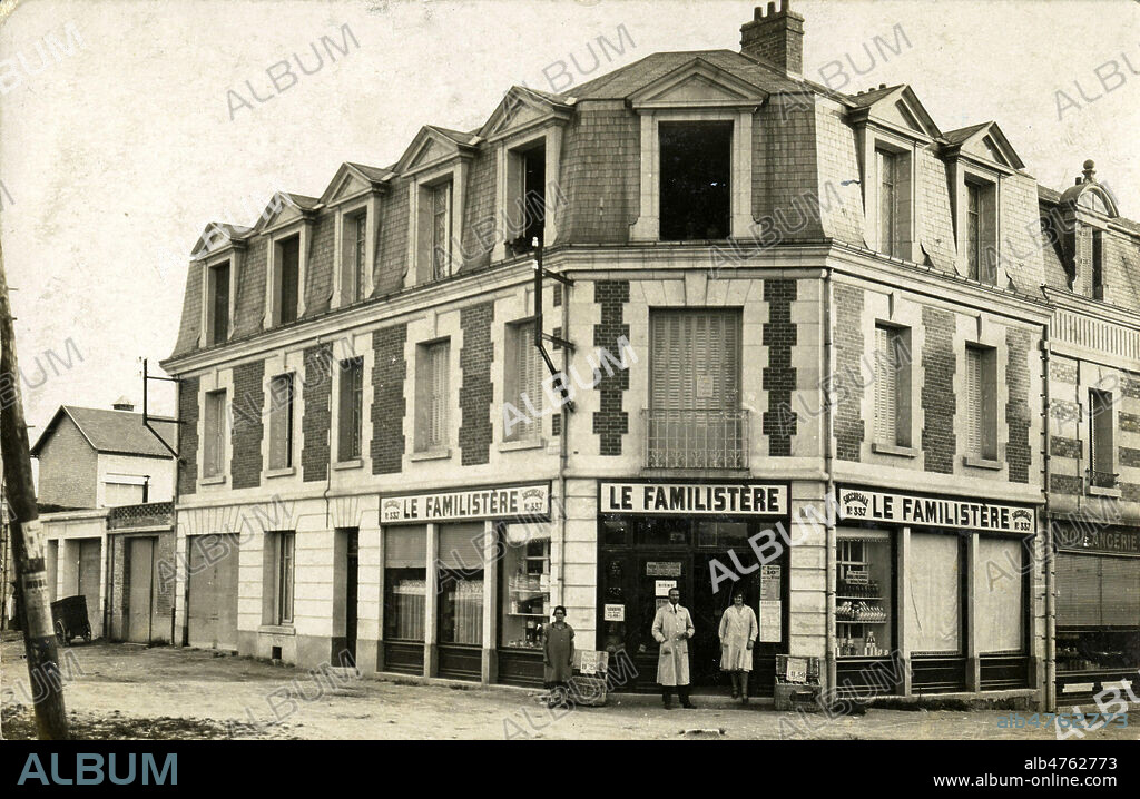 'Le Familistere' : un homme et deux femmes devant une epicerie. Photographie anonyme pour une carte postale vers 1920. Credit : Collection IM/KHARBINE-TAPABOR.