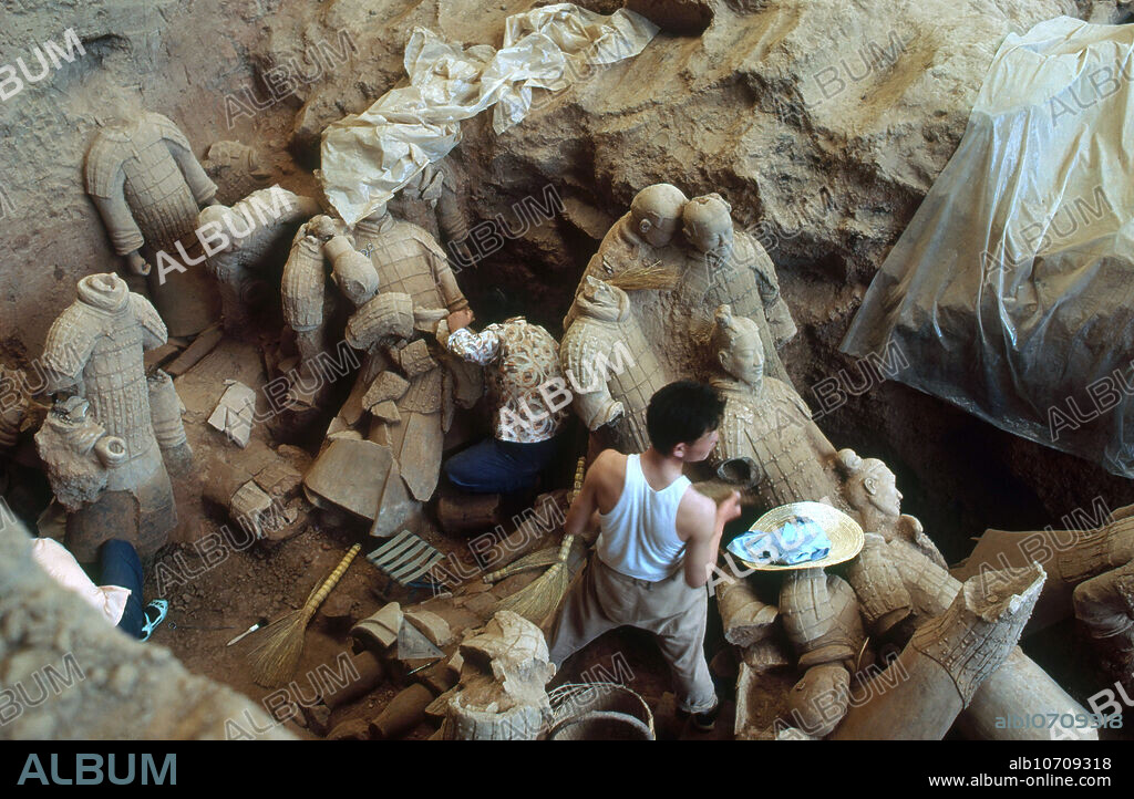 Excavation of the Terracotta Guardian Army of Emperor Qin Shi Huang, near Xian (Sian), China. Qin Shi Huang was king of the Chinese State of Qin from 247 BCE to 221 BCE and became the first emperor of a unified China in 221 BCE, ruling until his death in 210 BCE. He was buried in his mausoleum with a terracotta army of over 8000 soldiers, 130 chariots, 520 horses and 150 cavalry horses. They were intended to help Qin Shi rule another empire in the afterlife. The army was discovered in 1974 by local farmers who were drilling for water. The place is now a major archaeological site and tourist attraction.