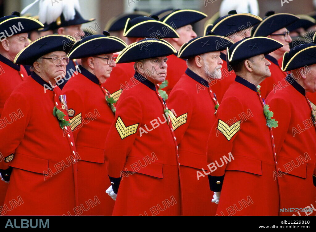 Chelsea Pensioners, wearing their traditional uniform of red coat and black tricorn hat, standing outside the Royal Hospital in Chelsea during the Founder's Day Parade.
