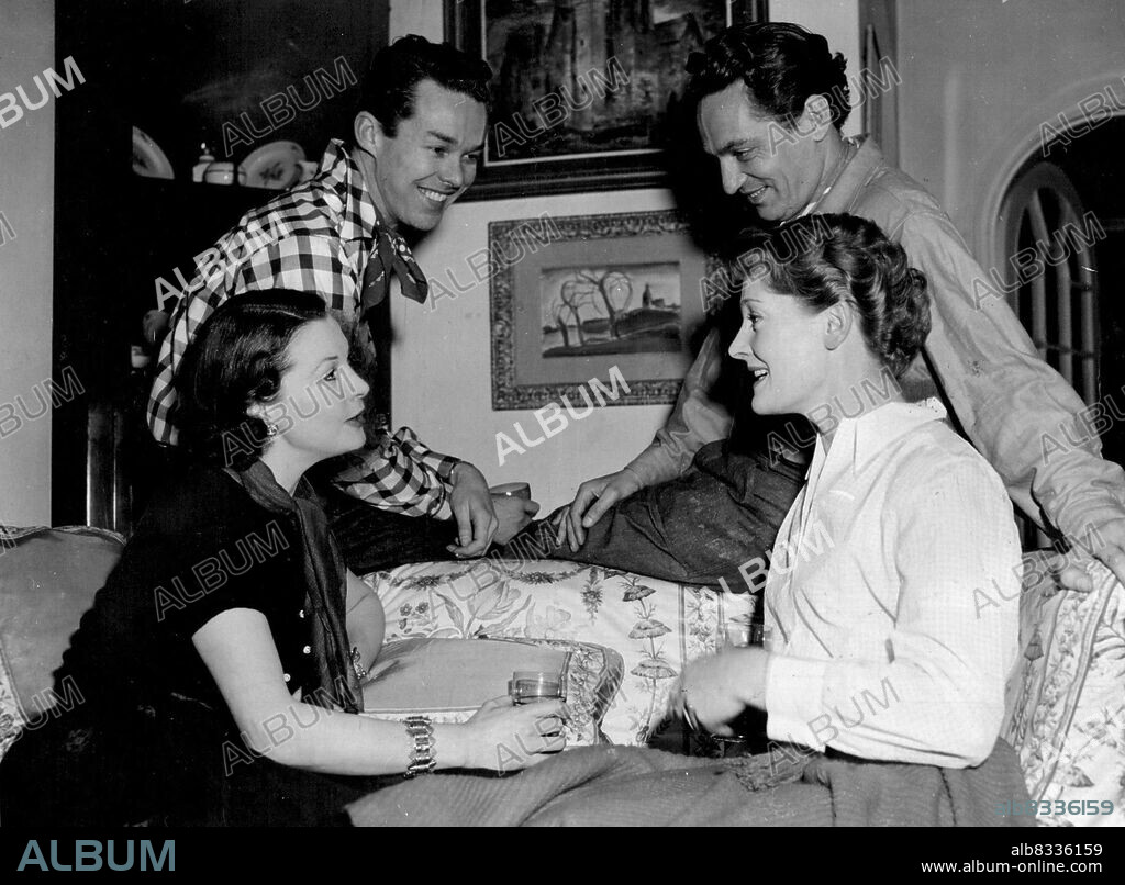 Lady Olivier, Mrs. Michael Redgrave, and standing, left to right: Mr. John Tullis and Mr. Peter Finch.Lady Olivier and party to square dancing at the Chelsea Town Hall. Before leaving for the dance they had a snack at the Oliviers' home. Before going on to a square-dance party, she relaxed in he Chelsea home over a drink with (L.to R.) actor John Tullis, Australian Peter Finch and the wife of film star Micheal Radgrave. January 8, 1953. (Photo by Daily Mail Contract Picture).