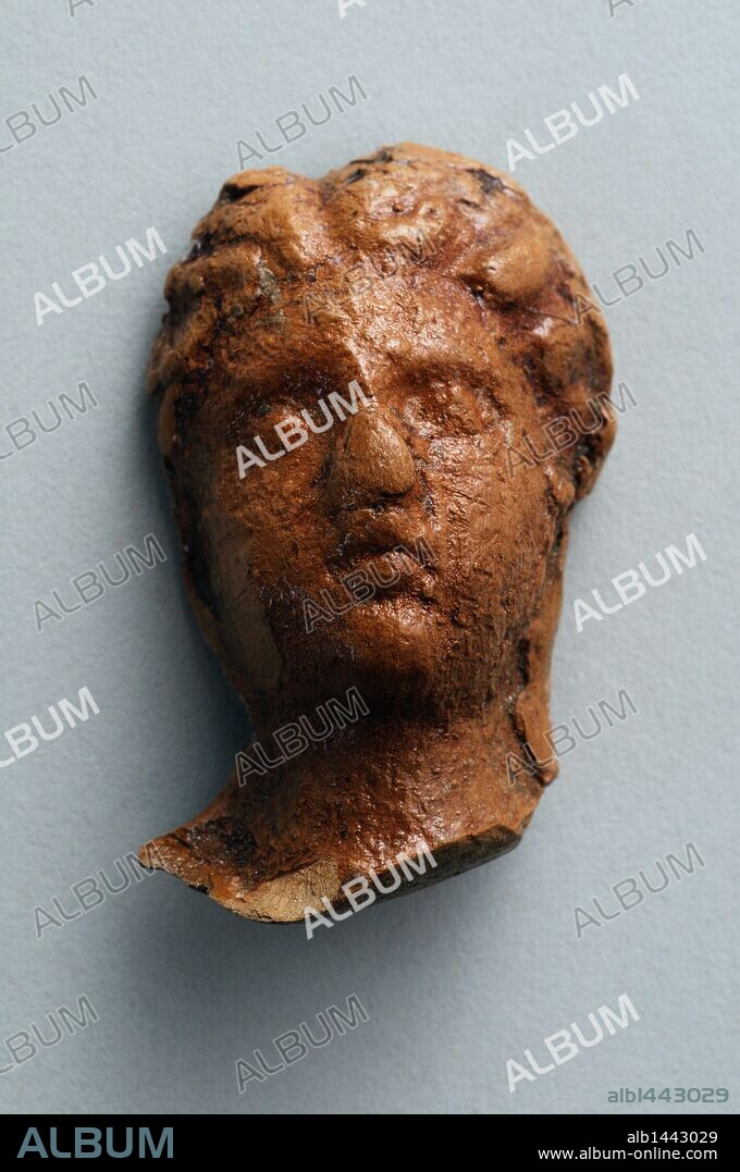 Head female of terracotta figurine with roman hairstyle. Height 3.6 cm Width 2, 3 cm (1 st - 3 rd CE ) - Roman period from  " House of Hyppolytus "- Archaeological site of Complutum in Alcalá de Henares ( Madrid ). SPAIN.