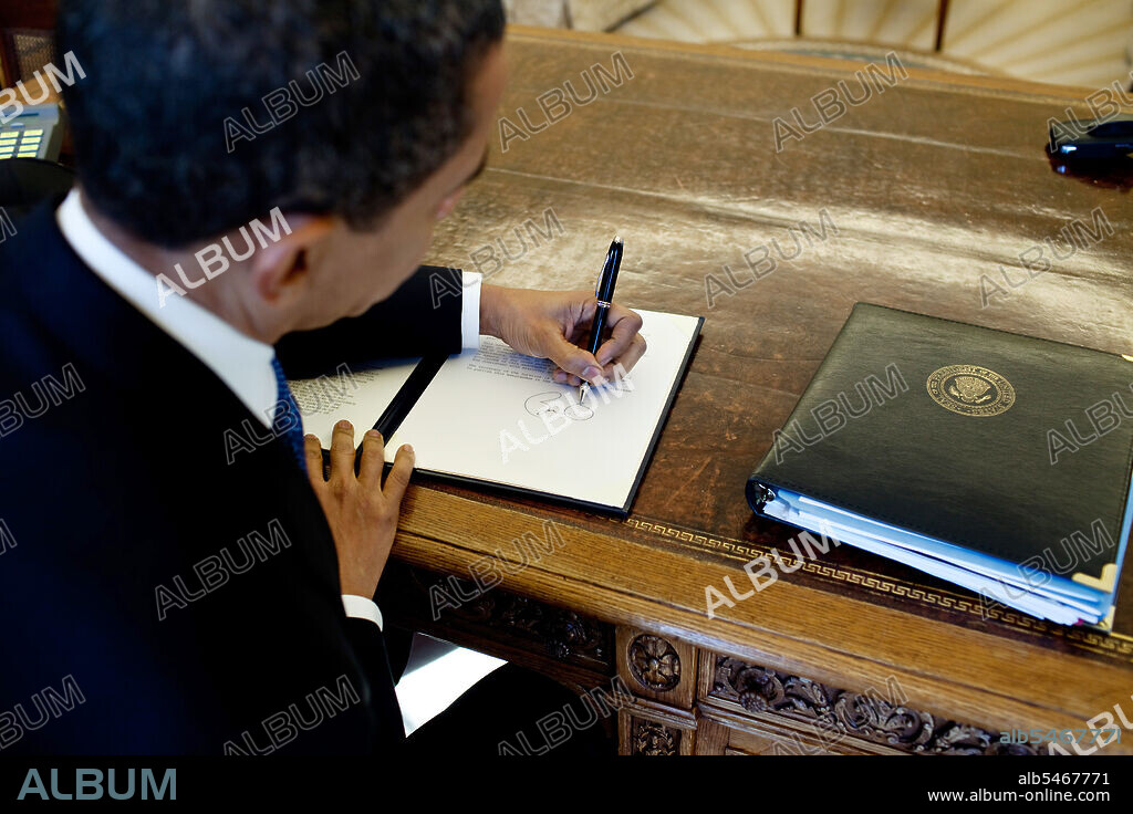 President Barack Obama writes at his desk in the Oval Office 3/3/09. .