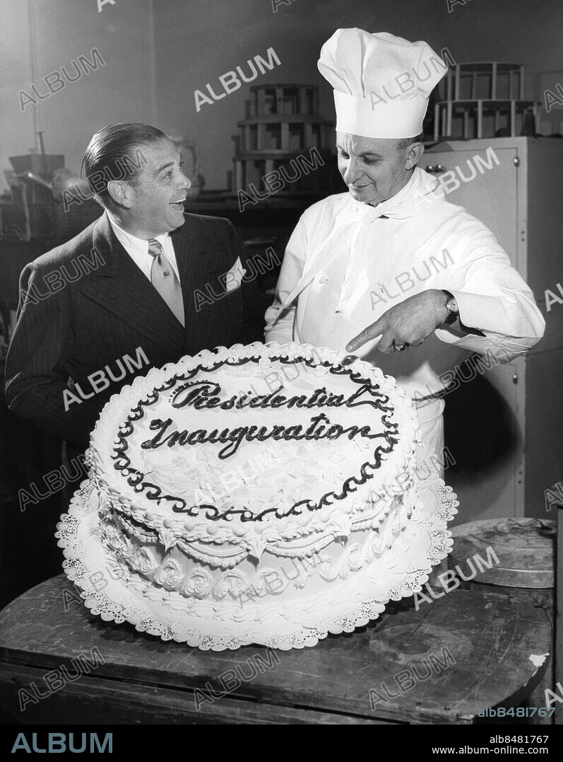 Orig. bildtext... PRESIDENTIAL PIECE DE RESISTANCE. Wash. D.C. A 100-pound cake, fit for a president, is the piece de resistance for tomorrow's inaugural festivities. Tenor Morton Downey is admiring the mammoth cake to which Amedio Toti, a Washington hotel chef is adoing the final artistic touches. 1.19.49. Not. Presidentvalet i USA 1948: Trumans installation som president i jan 1949. Anm. Bakverk Beundran Glasyr Kockmössor Köksmästare Peka Presidential Inauguration Sångare Texter Tårtor persons: AMEDIO TOTI;MORTON DOWNEY sites: USA;WASHINGTON D C.