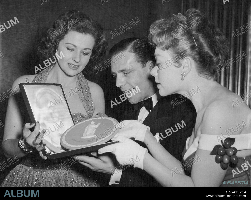 Newcomer Norman Gets His Award - Seasoned actresses Margaret Lockwood (left) and Glynis Johns admire with Norman Wisdom the British Film Academy Award he has Just received for being the 'Most Promising Newcomer' to the screen. The award plaques were presented this evening (Thursday) at the Odeon, Leicester Square. March 25, 1954. (Photo by Reuterphoto).