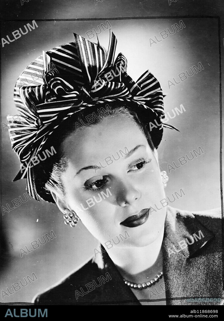 Gay roman-striped tarreta vies with the natural charm of Colombia star Adele Jergens who wears this striking hats in Swiss Straw. Combined with Adele's vivacious yet soignee personality, its a perfect time or cocktail combination. With pert bows to outline the brim of this attractive fashion, it is surely one of the most attractive off the face models ever designed. 7 January 1948.