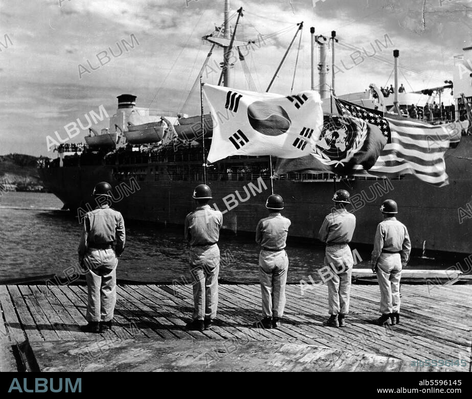 Korea-Krieg 1950-53. (Demokr. Volksrep. Nordkorea gegen Rep. Südkorea und UN-Truppen). Ankunft eines US-Passagierschiffes mit Truppen an Bord: Empfang durch eine Ehrenformation von US-Marines, mit den Flaggen Koreas, der USA und der UNO im Hafen. Foto, 1950.