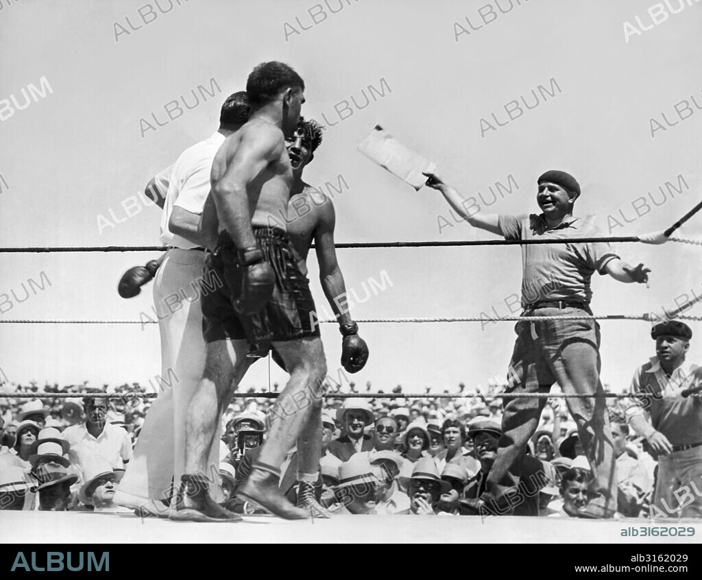 Reno, Nevada: July 4, 1931. Referee and former heavyweight champion Jack Dempsey awards the decision to Paulino Uzcudun after he fought a grueling 20 round battle against Max Baer in the Nevada sun. Dempsey is between the two fighters with Baer facing the camera.