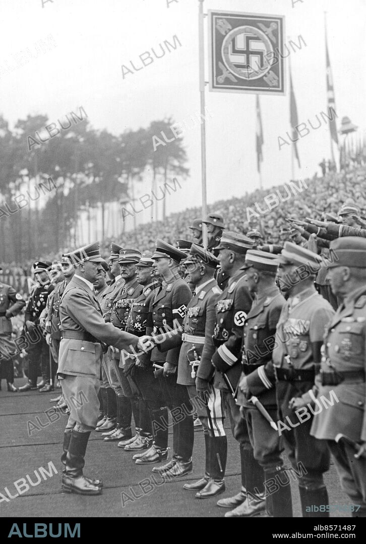 TYSKLAND NÜRNBERG 1937-09-09. Orig. bildtext... DER FÜHRER LEGTE DEN GRUNDSTEIN ZUR GEWALTIGSTEN SPORTSTÄTTE DER WELT. Der Führer und Reichskanzler legte am Donnerstag vormittag den Grundstein für das Deutsche Stadion auf dem Reichsparteitagsgelände, das über 400 000 Zuschauer fassen wird und nach seiner Fertigstellung die grösste Kampfstätte der Welt sein wird. Gleichzeitig hat der Führer die im Vorigen Jahr von ihm angeordneten Nationalsozialistischen Kampfspiele eröffnet. U.B.z. Der Führer begrüsst die Ehrengäste durch Handschlag, unter ihnen bemerkt mann: Reichsarbeitsführer Hierl, Reichssportführer v. Tschammer-Osten, Generalleutnant Christiansen, Reichsjugenführer Baldur von Schirach, Korpsführer Hühnlein, Reichsstatthalter Ritter von Epp, Reichsschatzmeister Schwarz. Foto: Scherl Bilderdienst / AB Text & Bilder / SVT / Kod: 5600 Mapp: Nürnbergs stadion (Tyskland) 525 G Anm. Deutsches Stadion, arkitekt Albert Speer, var tänkt att bli världens största idrottsarena. Arbetet påbörjades i september 1937 men blev aldrig färdigbyggt. Bildserier Fotoreportage Hakkors Handslag På rad Idrottsanläggningar persons: HANS VON TSCHAMMER UND OSTEN;KONSTANTIN HIERL;ADOLF HITLER;BALDUR VON SCHIRACH;ADOLF HÜHNLEIN;FRANZ RITTER VON EPP;FRANZ XAVER SCHWARZ sites: NÜRNBERG;TYSKLAND.