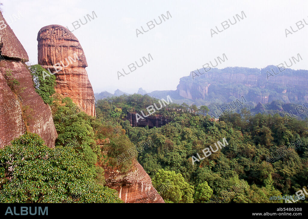 Danxia Mountain meaning Red Rosy Clouds Mountain, is a famous scenic area near Shaoguan city in the northern part of Guangdong Province. The area is formed from a reddish sandstone which has been eroded over time into a series of mountains surrounded by curvaceous cliffs and many unusual rock formations (Danxia Landform). There are a number of temples located on the mountains and many scenic walks. There is also a river winding through the mountains on which boat trips can be taken to enjoy the scenery. Particularly noted are two formations: a stone pillar called the Yangyuan (male/father stone) that bears a resemblance to a phallus and the Yinyuan hole, which somewhat resembles labia.