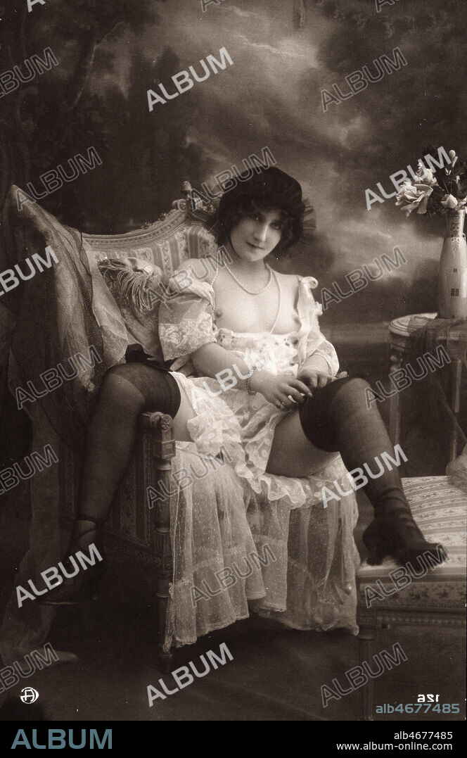 Femme remontant ses bas, seins nus dans un fauteuil, Photo erotique de la Belle Epoque, vers 1900. Credit Collection Kharbine Tapabor.