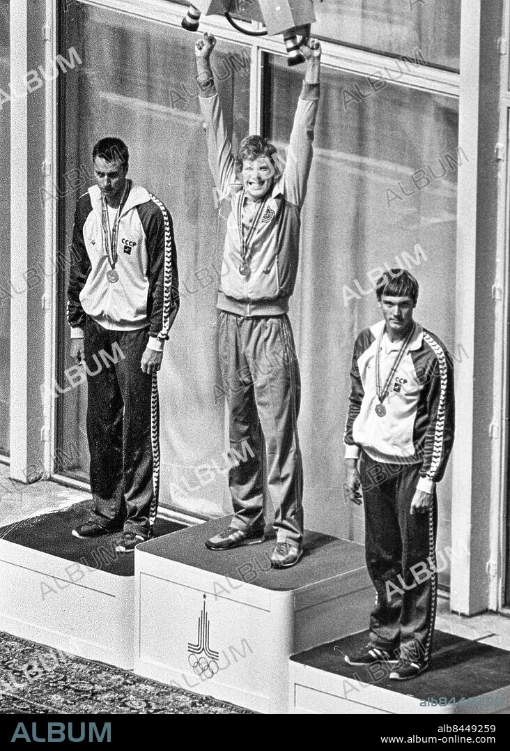 ARKIV MOSKVA 1980-07-21. Den svenske simmaren Bengt Baron jublar överst på prispallen med armarna i skyn och guldmedaljen runt halsen vid medaljceremonin efter att ha vunnit OS-guld på herrarnas 100 meter ryggsim vid de olympiska sommarspelen i Moskva, Sovjetunionen, 21:a juli 1980. Baron flankeras på pallen av tvåan ryssen Viktor Kuznetsov (t. v.) och trean ryssen Vladimir Dolgov (t. h.). Foto: Jan Collsiöö / TT / Kod: 1001.