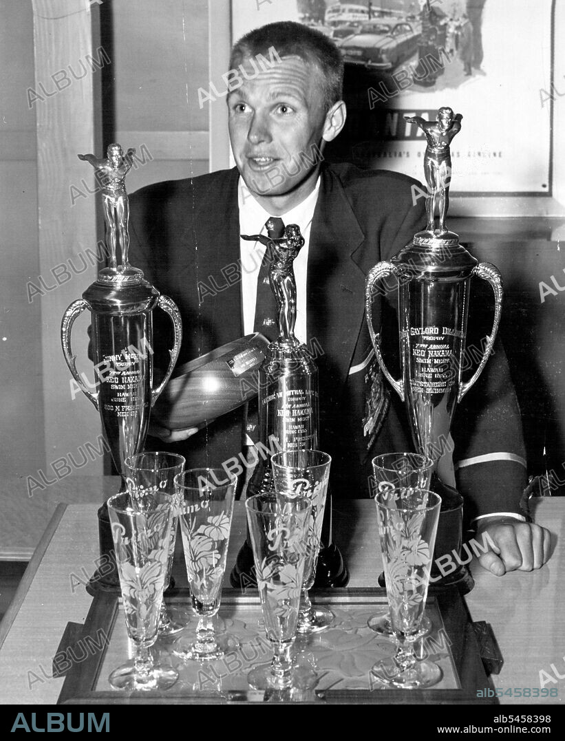 Swimming champion Jon Henricks shows the trophies he brought home yesterday from his record breaking visit to Hawaii. July 4, 1955.