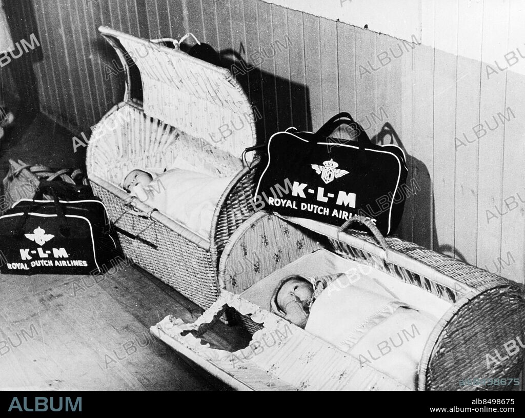 Orig. bildtext... BABES IN THE CLOUDS ROYAL SUITE. These babies traveled by air from Curacao in the neat bassinets provided by the Royal Dutch Airlines. Each bassinet is accompanied by a neat hold-all containing diapers and other essentials. The bassinets can be carried like hand luggage. Baby at right is nonchalantly sucking its thumb as it ponders, no doubt, on the rapid march of progress. Anm. Curious Moments s.247 CD15 173.8 Resenärer Bagage Korgar KLM K-L-M Royal Dutch Airlines sites: USA.