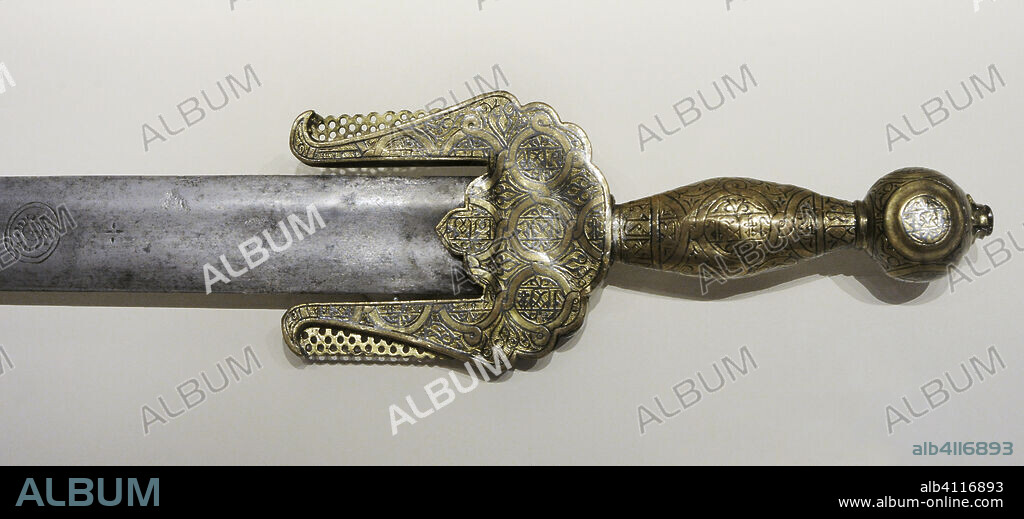 Jineta sword. Nasrid sword type that was introduced in Al-Andalus by the Zenata, one of the Berber tribes that went to the aid of the Caliphate regime in their fight against the Christian armies. 14th century. Steel, bronze and silver. Detail of the hilt with enameled and nielloed decoration, in the form of intertwined circular bands, superimposed on other transversal and longitudinal bands with scripts alluding to God. From the Church of San Marcelo (León, Spain). National Archaeological Museum. Madrid. Spain.