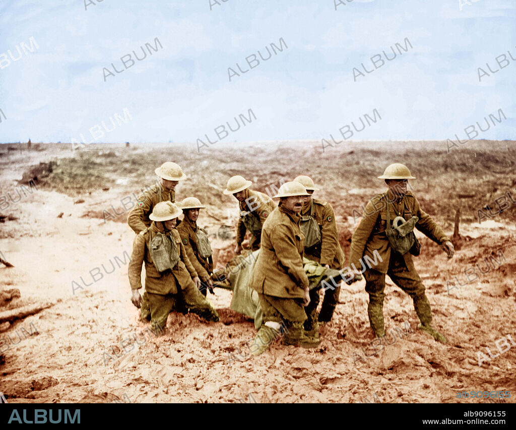 WW1: The common enemy on the Western Front was mud. These stretcher bearers are bringing in a wounded soldier. The mud sometimes reaches their knees. Colourised photograph.