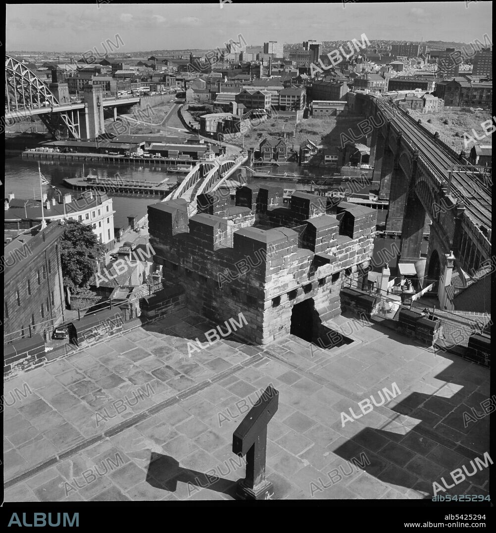 URSULA CLARK. Castle Keep, Castle Garth, Newcastle Upon Tyne, c1955-c1980. A cityscape of Newcastle, looking south over the River Tyne from the roof of Castle Garth Keep. The keep was built between 1168 and 1178, with the roof and battlements added c1811 by Newcastle Corporation. It was later restored c1848 for the Society of Antiquaries of Newcastle. The tower is square in plan with three storeys. In the foreground is the River Tyne, with the Tyne Bridge on the left, Swing Bridge, and High Level Bridge on the right. The image continues looking south.