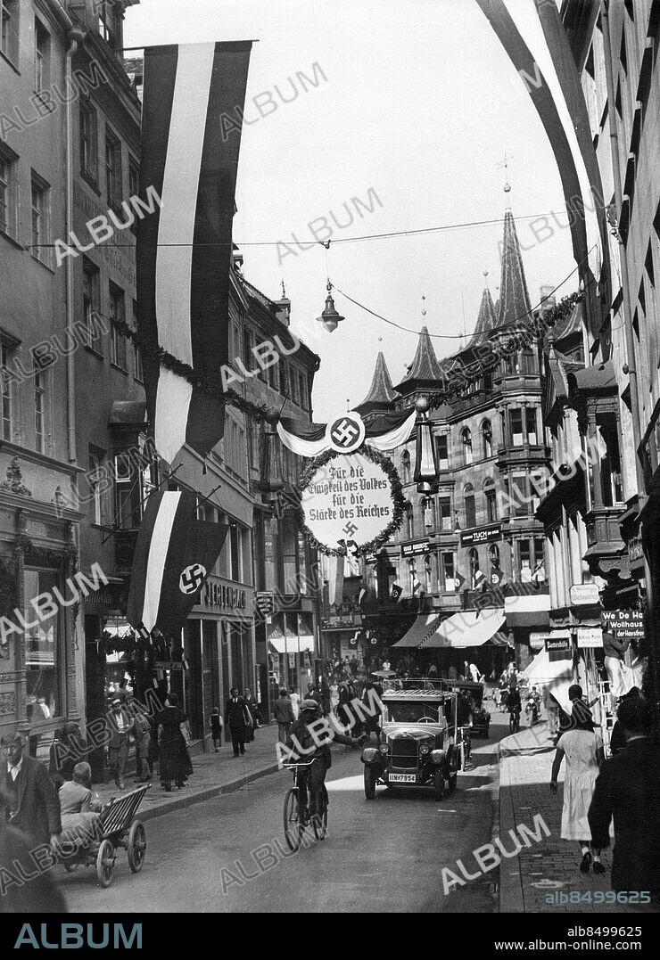 TYSKLAND NÜRNBERG 1933-08-30. Orig. bildtext... DIE REICHSTAGUNG DER NSDAP IN NÜRNBERG, DER GRÖSSTE PARTEITAG DER WELT. 30.8.33. Das Bild der alten Parteistadt im Festgewand: Blick durch die mit Girlanden und Fahnen geschmückten Strassen. Foto: Robert Sennecke / AB Text & Bilder / SVT / Kod: 5600 Mapp: Rikspartidagarna, Nürnberg tom 1933 4367 A Bildserier Fotoreportage Hakkors sites: TYSKLAND;NÜRNBERG.