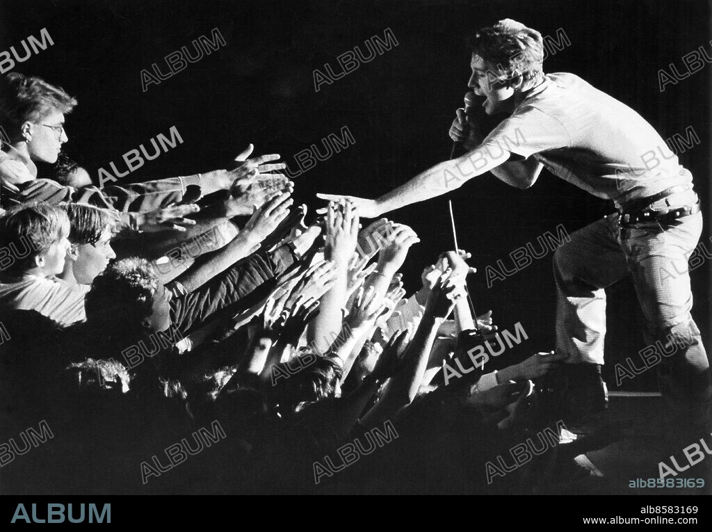 STOCKHOLM 1984-03-24. Jim Kerr i rockgruppen Simple Minds strcker ut en hand till publiken under en konsert p Johanneshovs isstadion.. Foto: Arne Adler / EXP / TT / Kod: 62. **AFTONBLADET OUT**.
