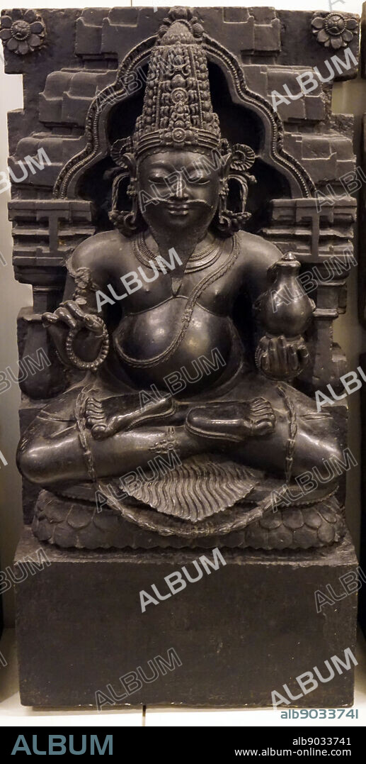 Sculpture of the Indian planet of the Jupiter (Brihaspati), shown as a portly, bearded priest, holding a water pot in one hand and prayer beads in another. Dated 17th Century.