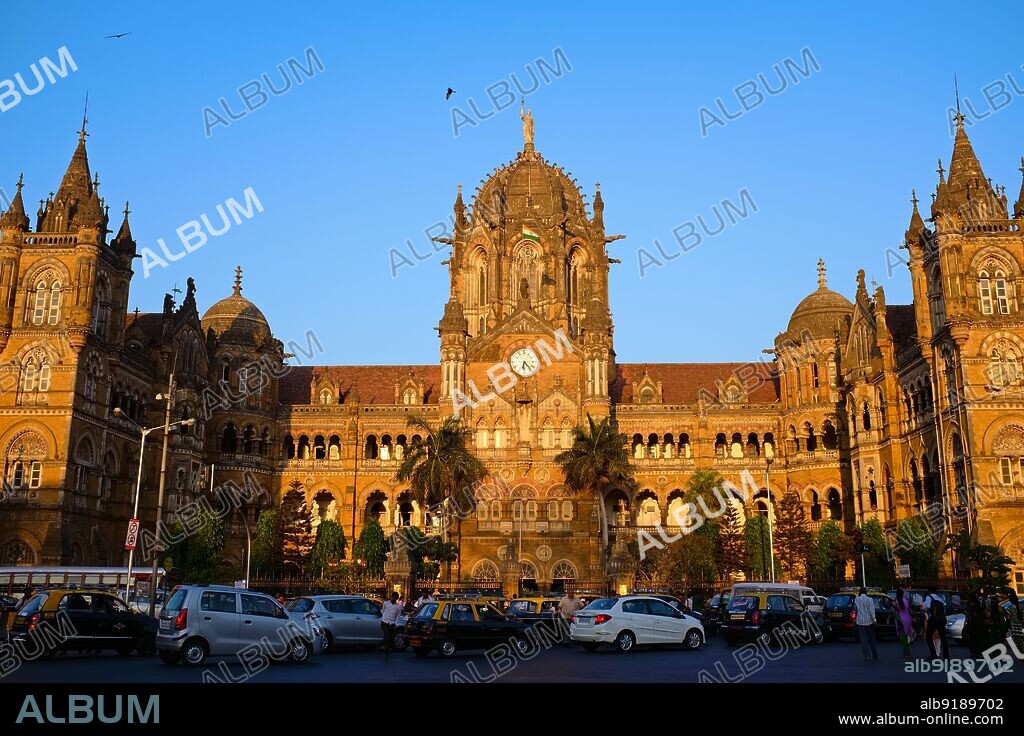 India: A frontal view (eastern flank) of Chhatrapati Shivaji Maharaj Terminus (CSMT) in Mumbai, a UNESCO World Heritage Site and the city's busiest railway station. This impressive railway station, formerly named Victoria Terminus, was built between 1878 and 1887, the station is an example of Victorian Italian Gothic style and was modelled on St. Pancras Station in London. The roof has church-like little spires and an impressive, gothic-style central dome. The terminus was designed by Frederick William Stevens from an initial design by Axel Haig.