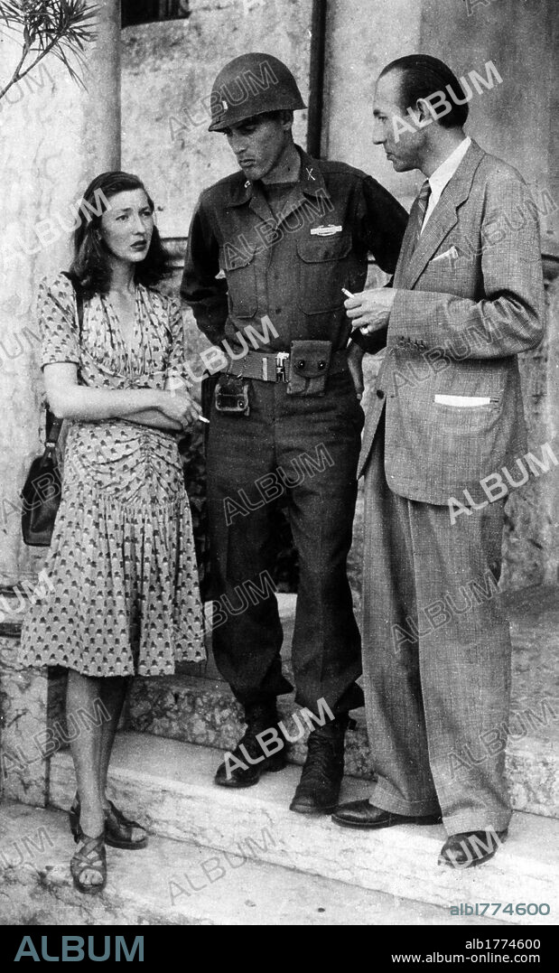 Corinne Luchaire with her father Jean and a soldier. An American officer posing together with the cinema actress Corinne Luchaire and her father Jean Luchaire captured near Merano by Allied troops. Merano, May 1945.