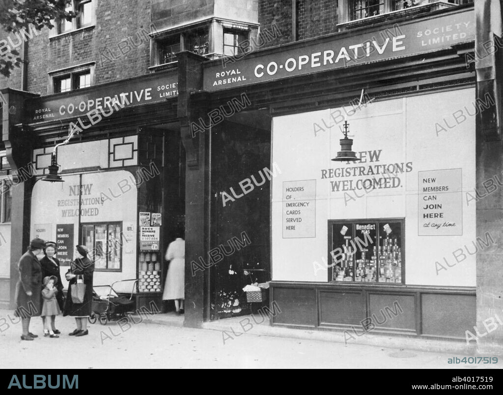 Exterior of the Royal Arsenal Co-operative Society Ltd, Old Kent Road, London, 1946. A group of women chat outside. The windows advertise for new registrations and state that holders of emergency ration cards will be served. Rationing continued for some time after WWII.