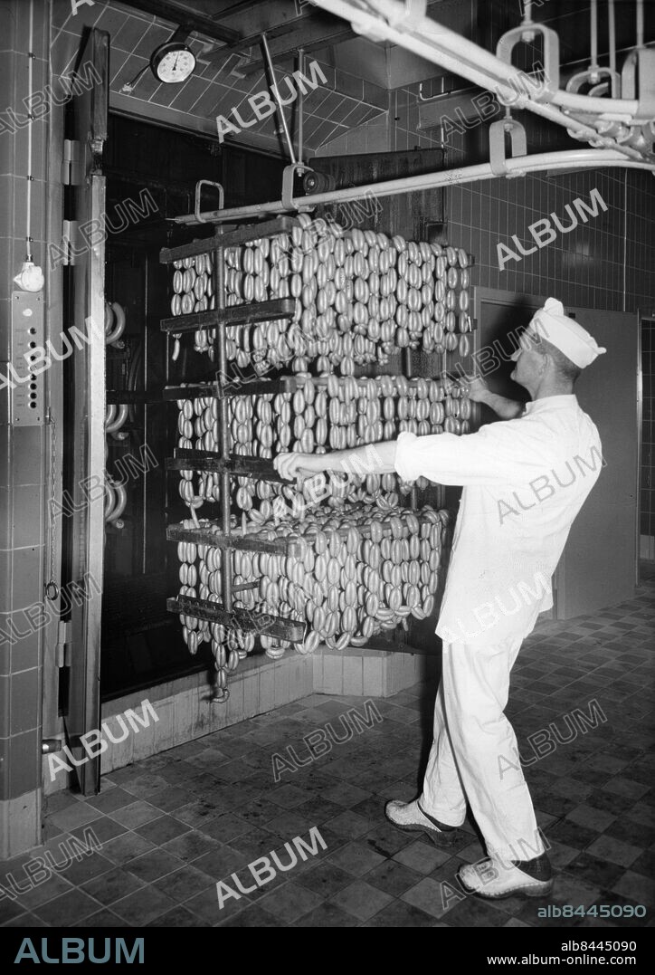 KF Kooperativa Förbundets charkuterifabrik i Malmö 1961.. Rökmästare Harry Sandberg tömmer en tornrök på prinskorv.. Foto: Sydsvenskan / IBL Bildbyrå.