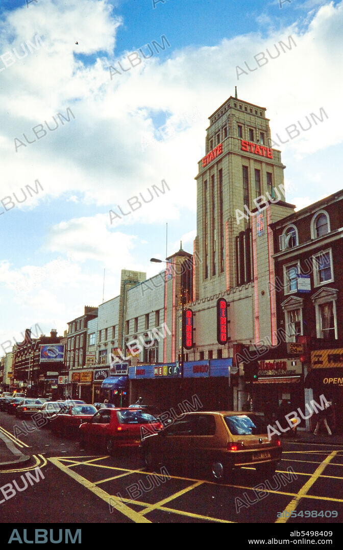 NORMAN WALLEY. Mecca Bingo Club, Kilburn High Road, Kilburn, Brent, London, 1990-2004. The Mecca Bingo Club and Kilburn High Road viewed from the north. The Gaumont State Theatre was opened in 1937. It was one of the largest cinemas in Europe, and the largest in England, with a seating capacity of 4,004. The exterior design is reputedly inspired by the Empire State Building in New York. The building was later divided into a dance hall, cinema and bingo hall, before being used solely as a bingo hall from around 1990. In 2010 the building reopened as a church.