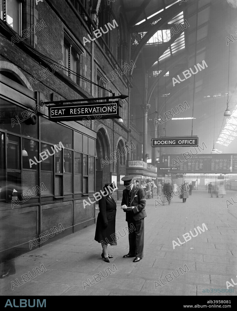Liverpool Street Station, London, 1950, the London terminus of the Great Eastern Railway. Signs show the location of the seat reservations and booking offices and the refreshment rooms; in the background is the departure board. A WH Smith kiosk is also visible. In the foreground a member of the station staff advises a passenger.