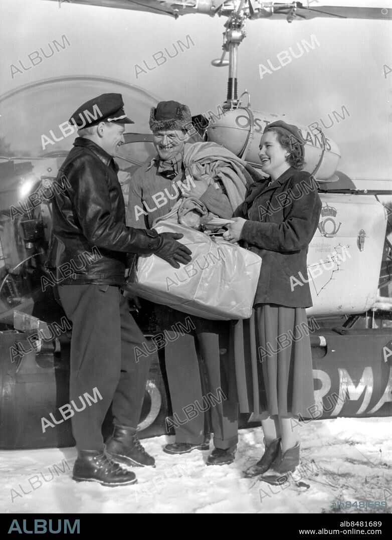 1958-02.. Orig. bildtext... POSTEN PER HELIKOPTER TILL SKÄRGÅRDEN 10 års jubilerar på måndagen och på bilden är det helikopterföraren Georg Carlsson som överlämnar jubileumsposten till postföreståndarinnan Fru Rigmor Sjöblom på Ingmarsö maken fiskaren Rolf Sjöblom är också med vid detta celebra tillfälle. Anm. Pjäxor Postleverans Leveranser Paket persons: ROLF SJÖBLOM;RIGMOR SJÖBLOM;GEORG CARLSSON sites: SVERIGE.