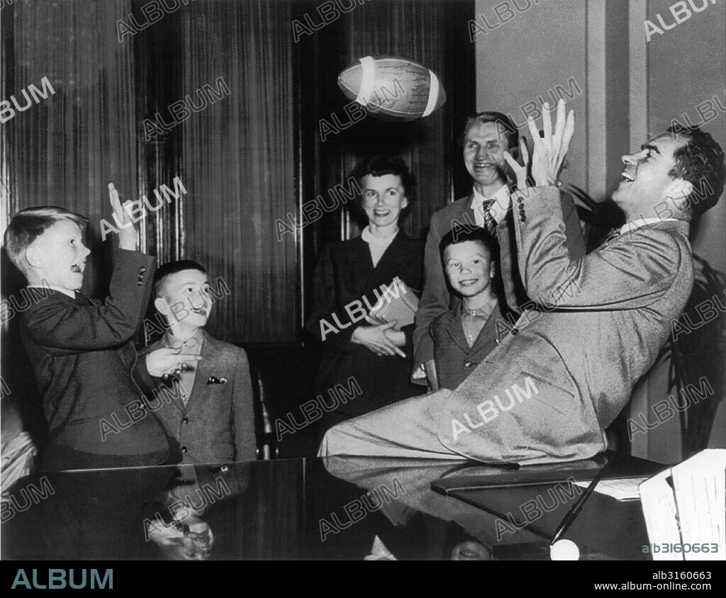 Washington, D.C.: c. 1950's Richard Nixon at his desk in Capitol, playing football with Andrus Suritis, one millionth refugee relocated by an international welfare organization.