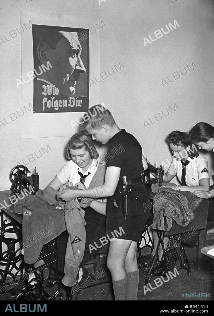 TYSKLAND BERLIN 1942-07-29. Orig. bildtext... JUGEND ÜBERHOLT WINTERKLEIDUNG UND SCHUHZEUG Die Hitlerjugend führt gegenwärtig im Einblick auf die kommende Winterzeit eine Aktion durch unter dem Motto "Schont Kleider und Schuhe - spart Spinnstoffe, Leder und Gummi". Alle HJ-Mädel und Jungen werden angehalten, die warmen Sommermonate für eine gründliche Ueberholung von Winterkleidung und Schuhzeug auszunützen. Zur Unterstützung für berufstätige Mütter werden in BDM-Nähstuben Kleidungsstücke geändert, ausgebessert und umgearbeitet. Unser Bild aus einer BDM-Nähstube in Berlin zeigt Mädel beim Ausbessern von Kleidungsstücken des Jungvolks. Foto: Scherl Bilderdienst / AB Text & Bilder / SVT / Kod: 5600 Mapp: Tyskland u.k.: Hitlerjugend under kriget V86:1 BDM - Bund Deutscher Mädel - kvinnlig motsvarighet till Hitlerjugend Knivar Knivhölster Affischer Sömnad Symaskiner Affisch med Hitler och texten: Wir folgen Dir sites: BERLIN;TYSKLAND.