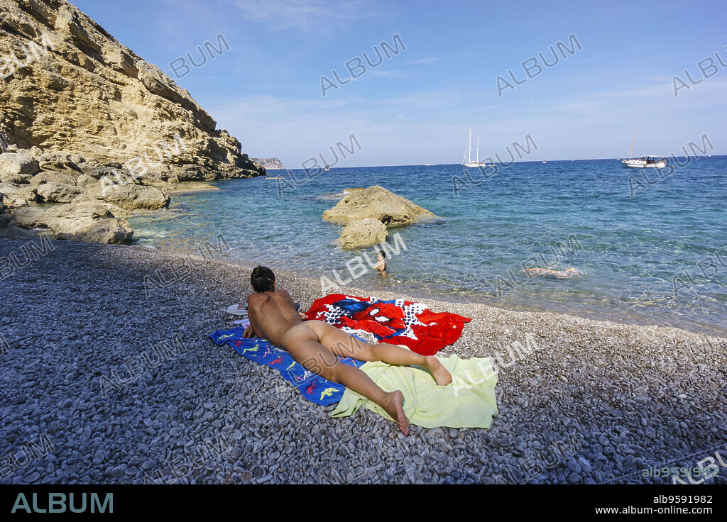 mujer soleandose desnuda,playa de Es Coll Baix, a los pies del Puig de Sa Talaia, Alcudia,islas baleares, Spain.