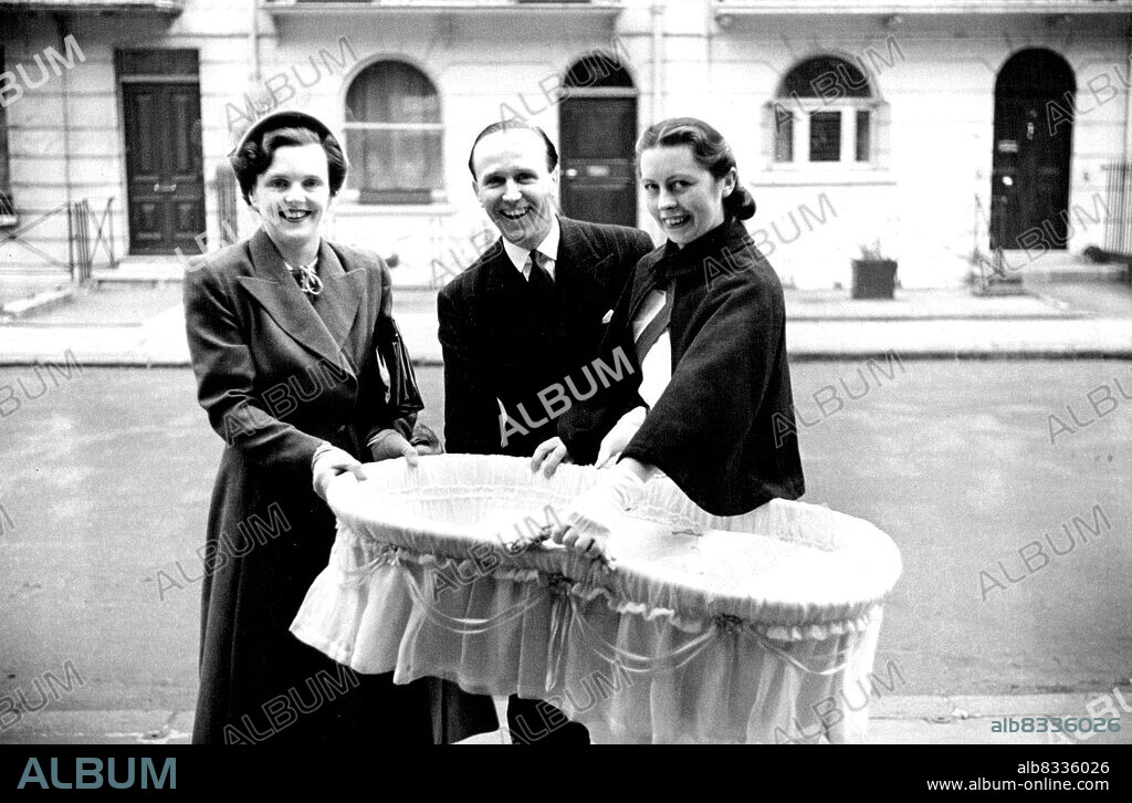 The Christening Over, Lieutenant and Mrs. Michael Parker with Nurse Hawthorne (from Ireland) leave, proudly carrying baby Julie in her cot. November 1, 1949. (Photo by Baron).