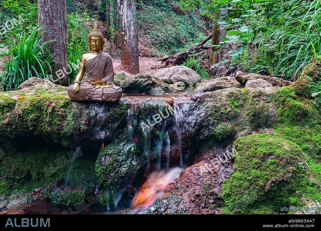 Buddha statue sitting in a mountain river meditating on a waterfall with green moss and rocks.
