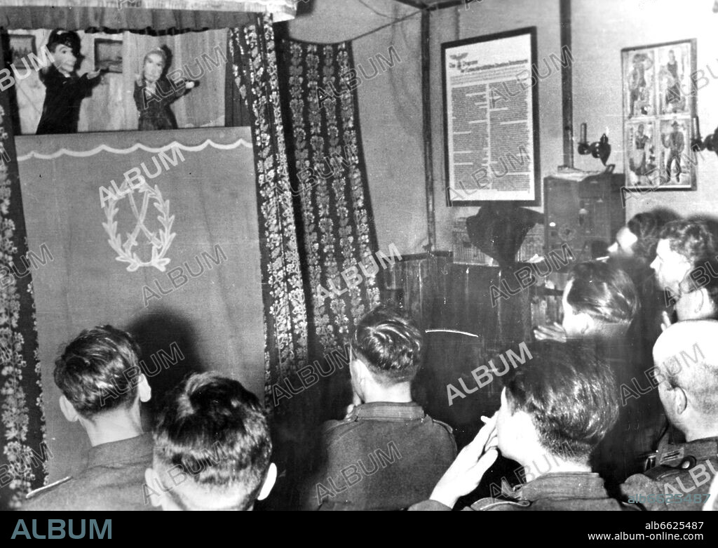 Soldiers are pictured during a Kasperle puppet theater performance as troop entertainment on the Eastern Front, published on 10 July 1943. The Nazi Propaganda! on the back of the image reads: "Kasperle puppet theater in the soldiers' quarter. With great joy, our mountain infrantry men on the Arctic Sea Front attend the performance." Photo. Fotoarchiv für Zeitgeschichte/Archiv. 10/07/1943