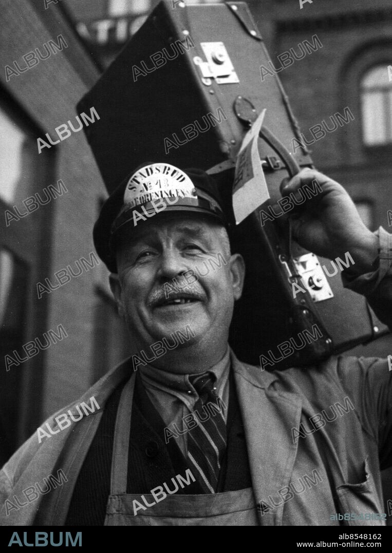 Stadsbudet Wilhelm Wiberg i Malmö som gjort 40 års tjänst 1947 .väska resväska på ryggen *** Local Caption *** A porter with a suitcase, Malmoe, Sweden 1946.