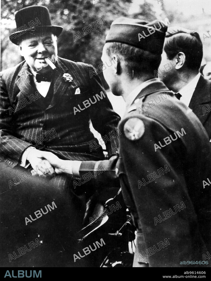 Winston Churchill, British statesman, World War II, 1939-1945. Churchill (1874-1965), Britain's wartime Prime Minister, smiling and smoking a cigar, shakes hands with a soldier.