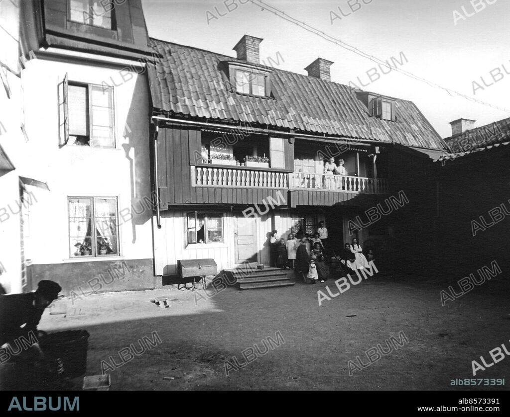 ARKIV STOCKHOLM 19060713.. Långa gatan 12 inpå gården Djurgården. Några kvinnor och barn utanför ett gammalt hus på gården vid Långa gatan 12.. Foto: Oscar Heimer / SVT / Kod: 5600. sv/v. Mapp: Djurgården, södra o. norra, Beckholmen D 1 - D 34. Balustrader Innergårdar Bakgårdar. H D:33.