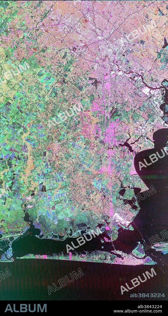 Image of Houston, Texas obtained by the Spaceborne Imaging Radar-C/X-band Synthetic Aperture Radar (SIR-C/X-SAR) flying aboard the space shuttle Endeavor. Central Houston appears pink and white in the upper portion of the image, outlined and crisscrossed by freeways. The pink areas designate urban development while the green-and blue-patterned areas are agricultural fields. Black areas are bodies of water, including Galveston Bay along the right edge and the Gulf of Mexico at the bottom of the image. Interstate 45 runs from top to bottom through the image. The narrow island at the bottom of the image is Galveston Island, with the city of Galveston at its northeast (right) end. The dark cross in the upper center of the image is Hobby Airport. Ellington Air Force Base is visible below Hobby on the other side of Interstate 45. Clear Lake is the dark body of water in the middle right of the image. The green square just north of Clear Lake is Johnson Space Center, home of Mission Control and the astronaut training facilities. The black rectangle with a white center that appears to the left of the city center is the Houston Astrodome.