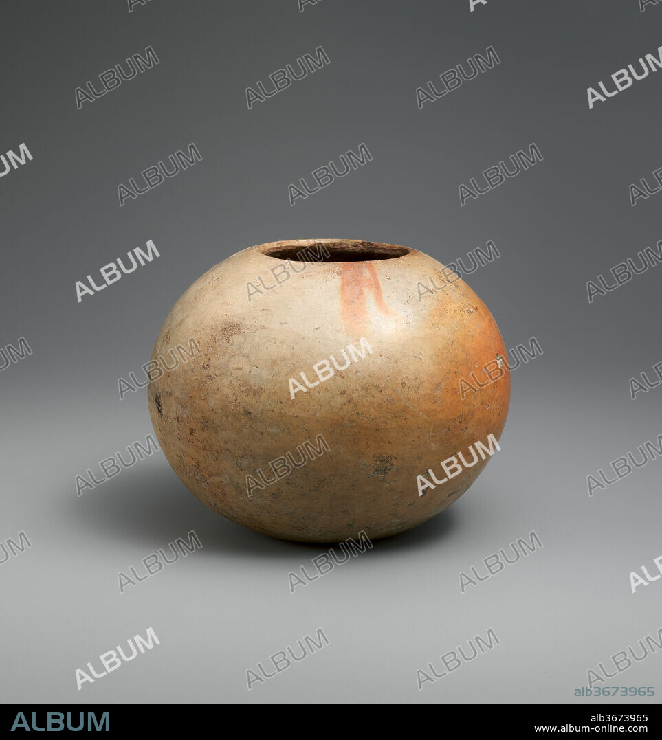 Bowl (Tecomate). Culture: Olmec. Dimensions: Diam. 4 3/4 in. (12 cm). Date: 12th-9th century B.C..
This bowl, reportedly from the site of Las Bocas, Puebla, Mexico, is in a full, round shape with a small opening at the top. Made of a kaolin-like clay, its walls are thin and burnished to a high gloss. It is undecorated, but the variegated color on its outer surface ranges from beige, to grey, to light brown and orange-red.