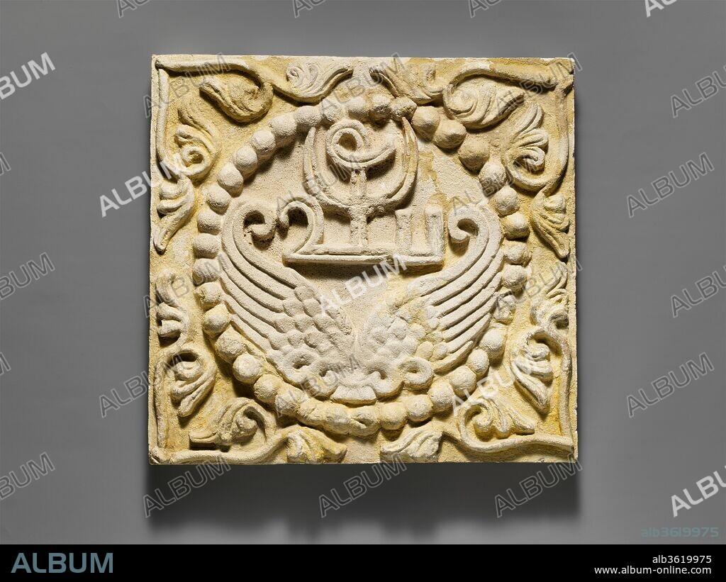 Wall panel with wings and a Pahlavi device encircled by pearls. Culture: Sasanian. Dimensions: H. 15 3/8 x W. 16 1/4 in. (39 x 41.3 cm). Date: ca. 6th century A.D..
Beginning in the 5th century, monograms became popular motifs used in the mold-made stucco wall panels that decorated the palaces and houses of the Sasanian elite, and many had symbolic meanings. This panel from the iwan (vaulted hall) of a large house at Umm ez-Za'tir, near the Taq-i Kisra at Ctesiphon, features a group of letters in the Persian script and a lunar crescent above symmetrical feathered wings and encircled by pearls: the motif very likely had protective significance. Half palmettes in the corners would have formed a complete design when this panel was placed within an arrangement with other similar ones. An identical panel is in Berlin in the Museum für Islamische Kunst, Staatliche Museen zu Berlin.