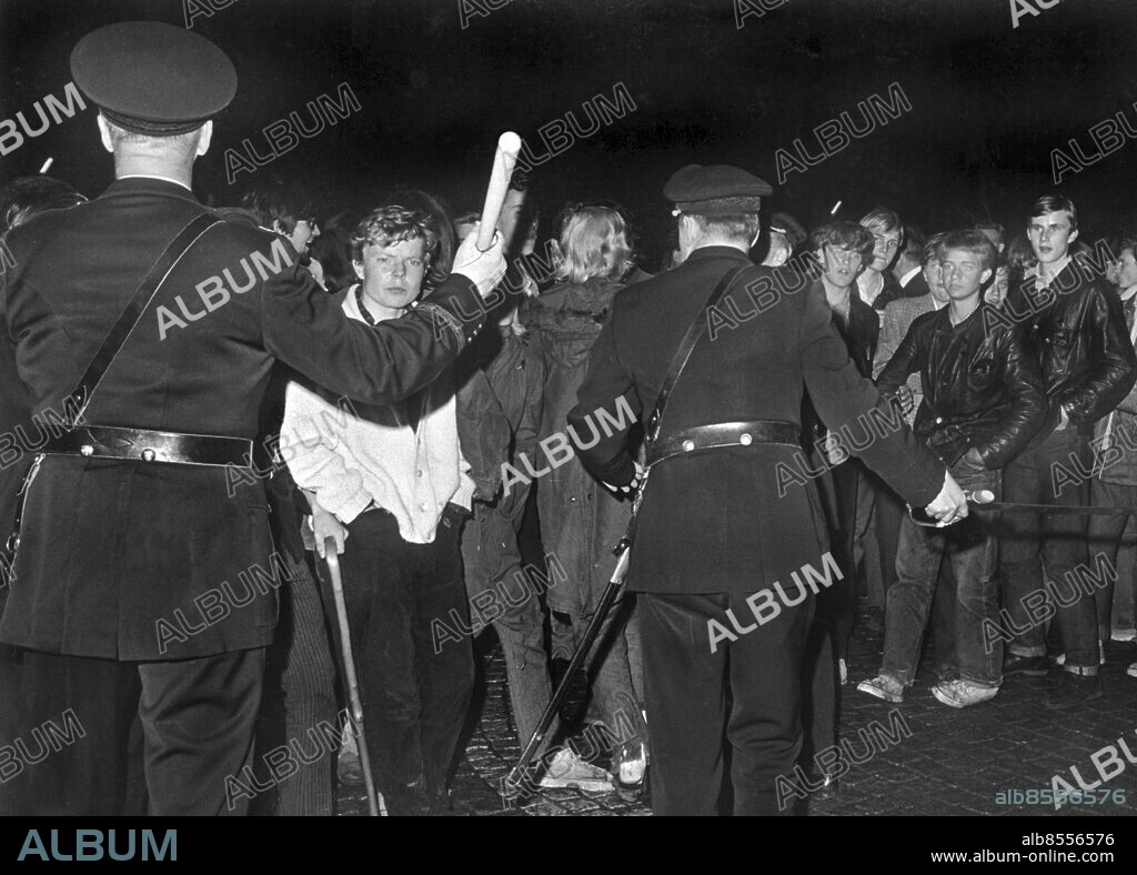 ARKIV STOCKHOLM 1965-08-28. Sammandrabbningar mellan ungdomar och polis på Hötorget i Stockholm 28:e augusti 1965 under de så kallade Hötorgskravallerna då hundratalet ungdomar, mestadels mods, samlats på Hötorget. De flesta hade tagit tunnelbanan från förorten och ungdomsgården in till centrum för att umgås. Polisen uppfattade situationen som störande av allmän ordning och konstaplar skickades ut för att upplösa folksamlingen. Modsen vägrade flytta på sig och omfattande kravaller utbröt. Flera skyltfönster krossades och bränder anlades på gatan.. Foto: G. Westerlind / SvD / TT / Kod: 11014.