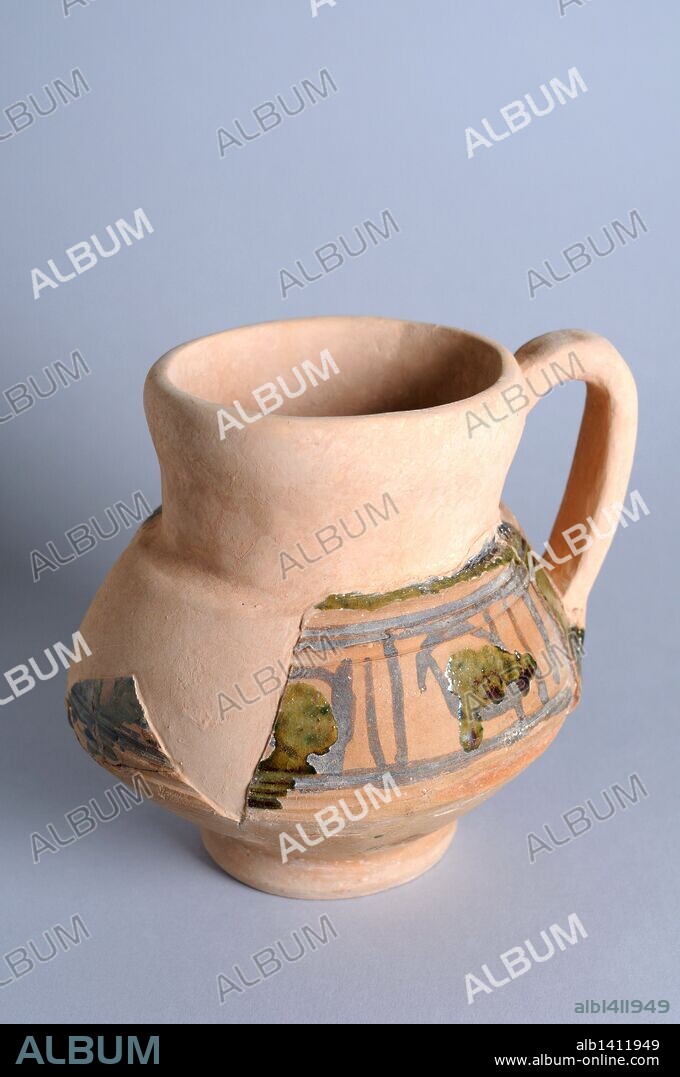 Jarra de cerámica de un asa y decoración vidriada a cuerda seca parcial. Altura 14 cm Diámetro boca 11 cm ( Siglos XII – XIII )- Epoca medieval procedente del Yacimiento arqueológico de la " Calle Seises " en Alcalá de Henares -" Museo del Burgo de Santiuste " ( Madrid ). ESPAÑA.