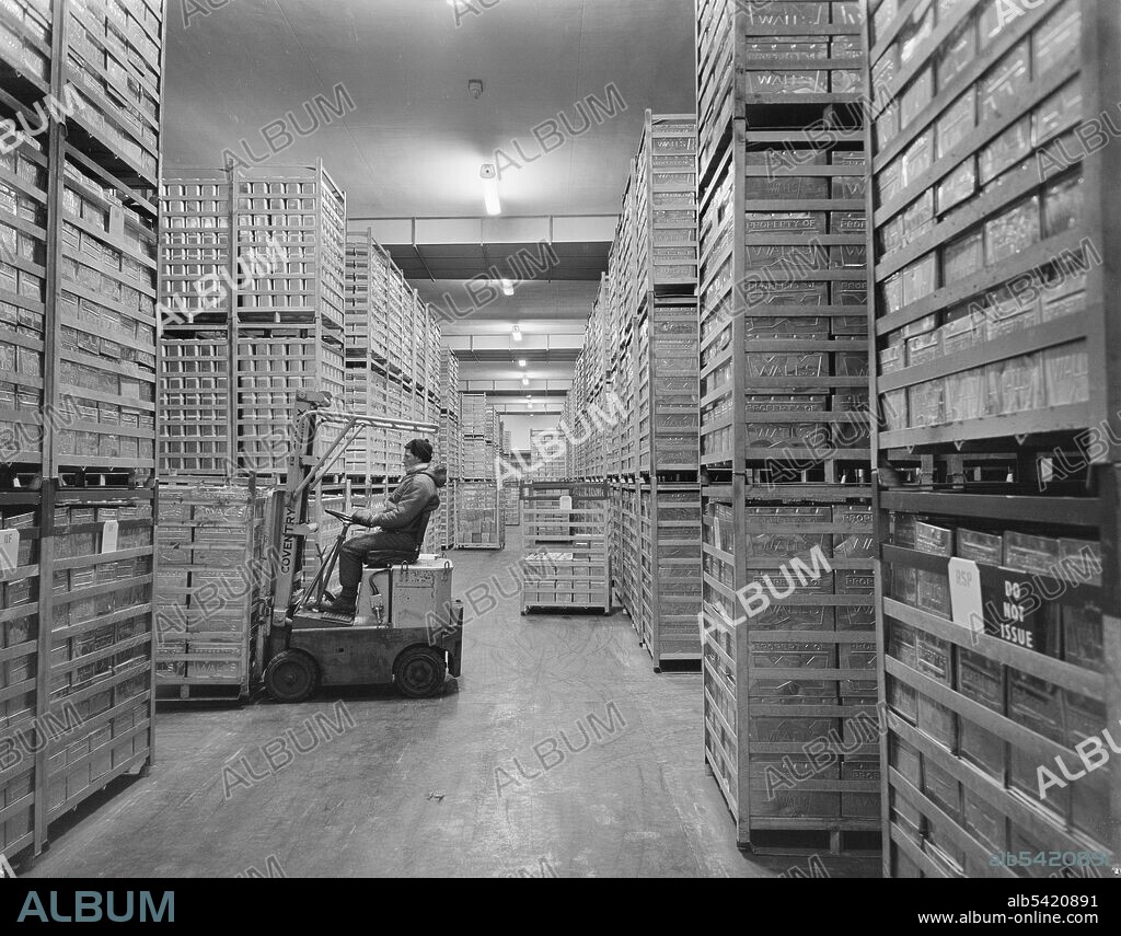 JOHN LAING PLC. A man operating a forklift to move a crate of metal containers in the cold store of the Wall's Ice Cream Factory. Work began in February 1959 on a new factory for T. Walls and Sons Limited on a 30 acre site at Barnwood. The £2 million project comprised buildings including the production block, workshops, offices, a canteen, boiler house, cold store, water tower, and engineers' shop.