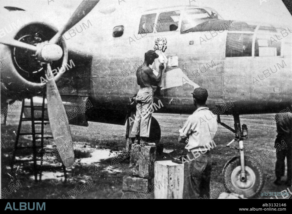 Australia:  c. 1943 A 5th AAF airman artist painting a pin-up on the nose of a B-25 bomber of the 80th Bomber Group stationed in Australia.